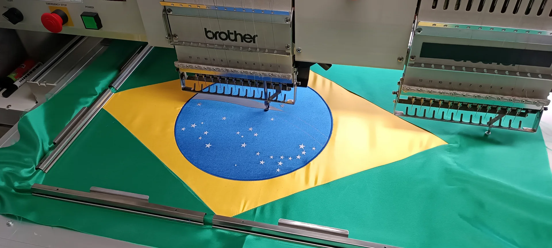 A brazil zászló központi motívumának hímzése bordűr keretben.
