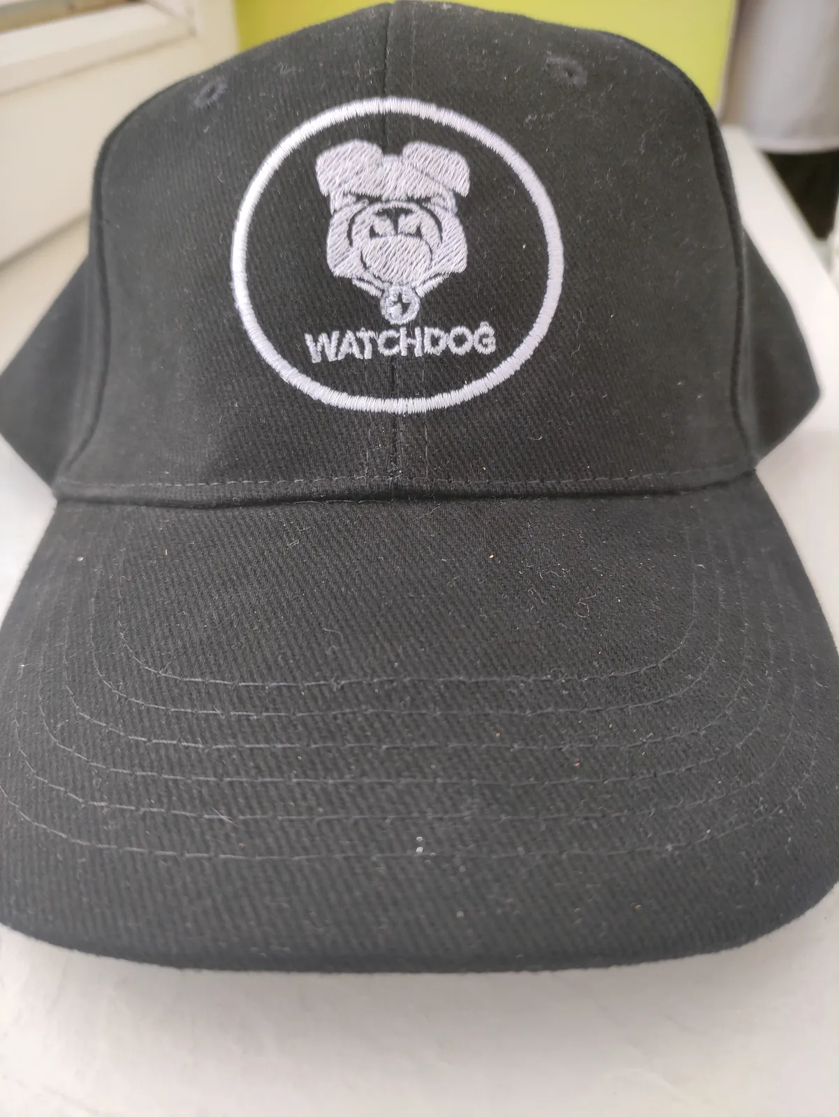Fehér logóhímzés fekete baseballsapkán.