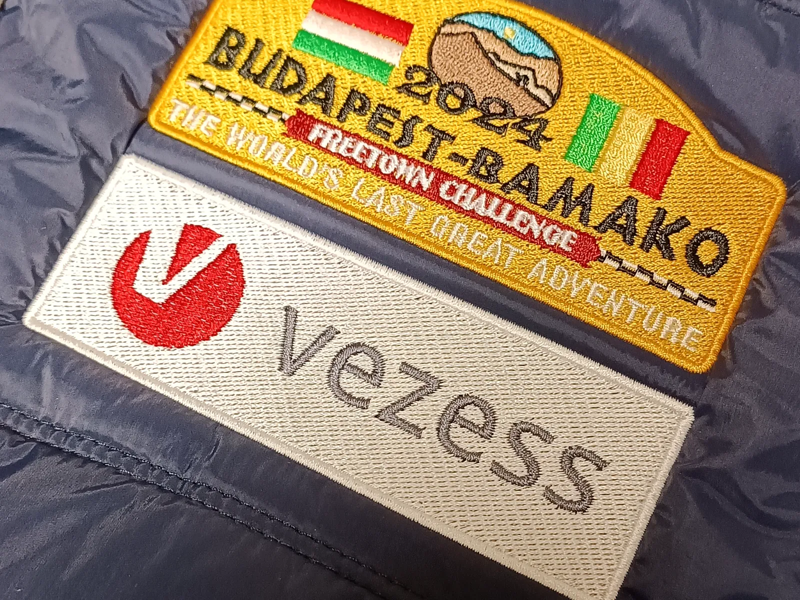 Budapest–Bamako és Vezess hímzés kék bélelt mellény elején.